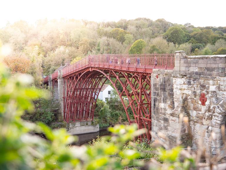 Image of the iron bridge, painted in red with trees in the background