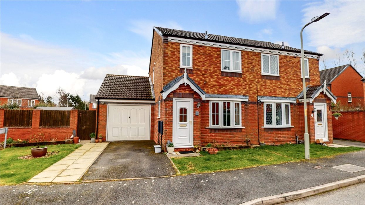Image of a semi detached house with white doors and windows plus a garage attached on the left hand side