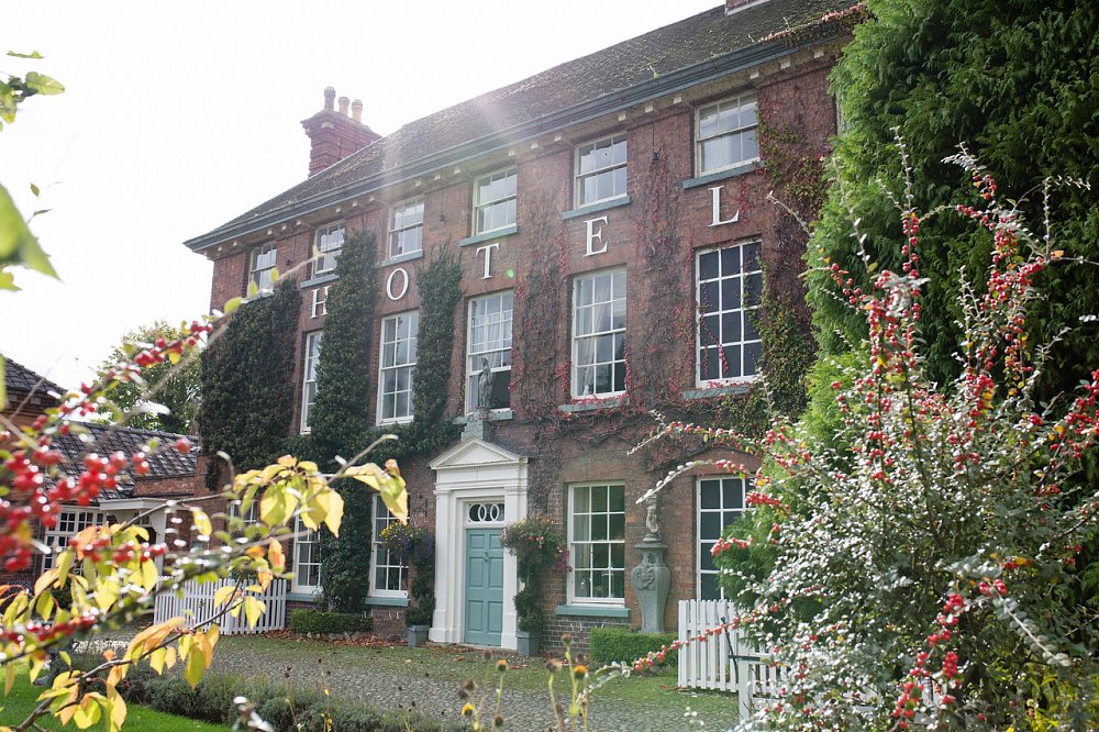 Front of the Mytton and Mermaid hotel, a brick building with a light blue door, white door frame and plants growing up the wall