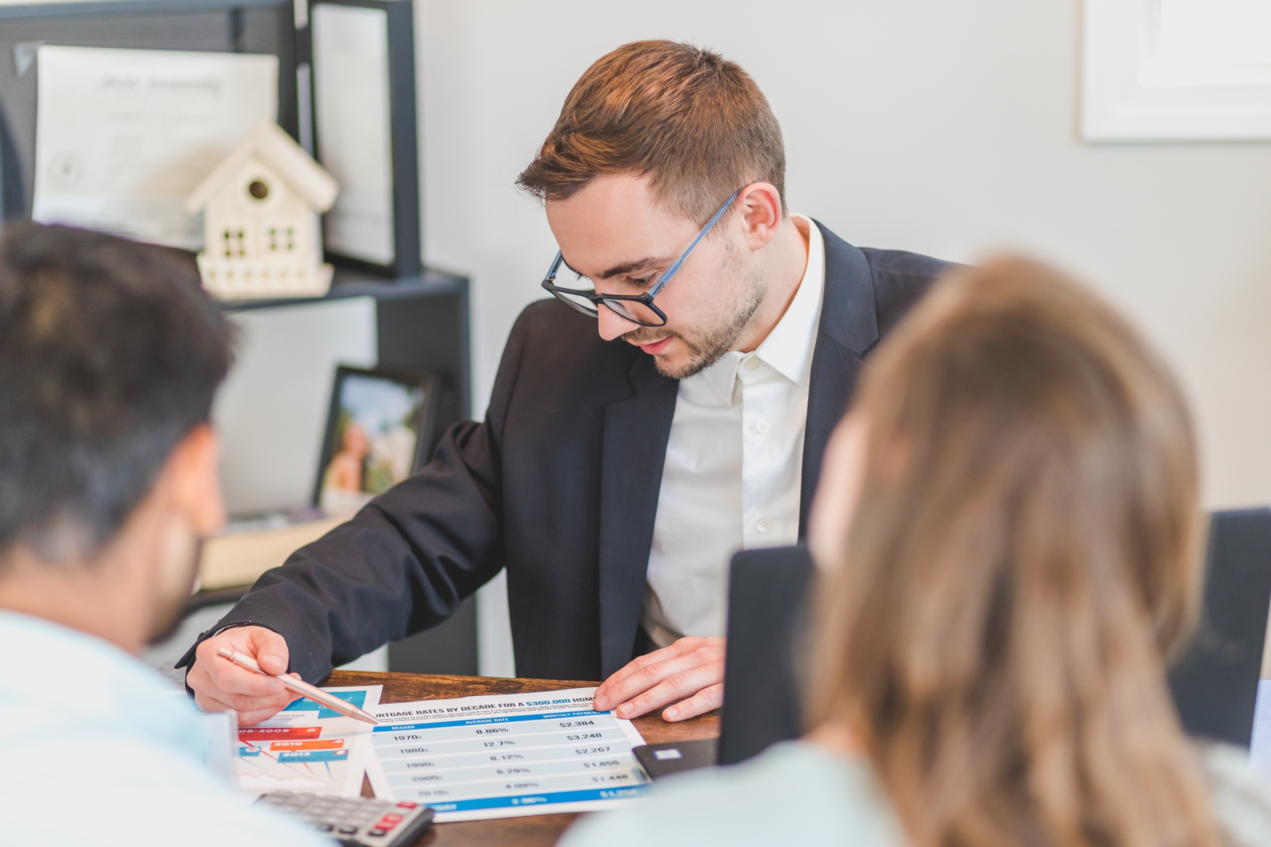 Image of an estate agents sitting at a desk with 2 clients looking at paperwork